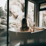 A soaking tub set in a window with a wild rock view
